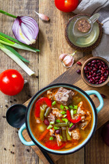 Traditional English thick soup with beef, beans and vegetables on a wooden table. Hot dinner or lunch. Top view flat lay.