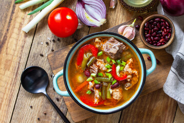 Traditional English thick soup with beef, beans and vegetables on a wooden table. Hot dinner or lunch. Top view flat lay. Copy space.