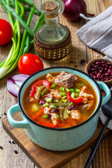 Traditional English thick soup with beef, beans and vegetables on a wooden table. Hot dinner or lunch. Top view flat lay.