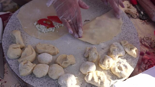 Adult woman making chebureks - roasts chebureks in pan, prepares meat pies, working with the dough and filling, close-up. Fried flatbread piadina naan pita tortilla shelpek cheburek. Street food.