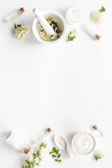 Fototapeta na wymiar White medical herbal cosmetics in flowers - with skin cream and bath salt