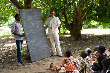 Teaching in a summer school in a remote West African village ; international humanitarian action, volunteering concept - obrazy, fototapety, plakaty