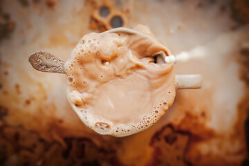 The human was pouring milk into a coffee mug. Mess in the kitchen. A pleasant invigorating drink for breakfast. Ice coffee.