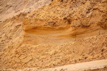 Textural sand, with  relief surface, multi-colored layers and different in size of granules, in outdoor sand career, after mining ore and sand for construction.