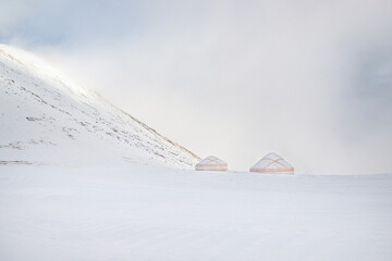 White-red patterned yurts in a snowy mountain valley
