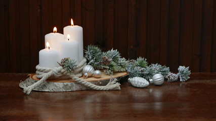 Weihnachtsdekoration: Weiße Kerzen mit Weihnachtskugeln auf einer Baumscheibe.