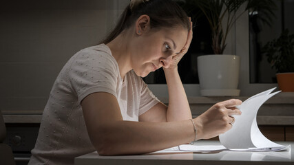 Portrait of stessed woman feeling frustrated while reading documents of divorce. Concept of financial difficulties, bankruptcy, taxes and rent payment.