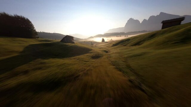 FPV drone flying above the trees at Alpi di Siusi, Seiser Alm. Dolomiti mountains, South Tirol, Dolomiten mountains view, Italian Alps. Clouds moving fast.