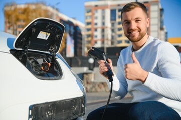 Man charges an electric car at the charging station