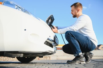 Man charges an electric car at the charging station