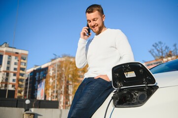 Man charges an electric car at the charging station