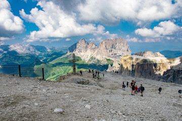 Dolomites, August, 2017, people on the top of Passo Fedaia, view of the green valley and mountains in the distance