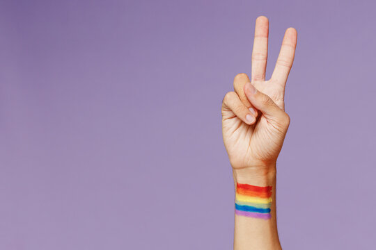 Cropped close up photo shot of gay man male hand arm showing victory v-sign friendly gesture isolated on plain pastel purple color background studio portrait. People lifestyle fashion lgbtq concept
