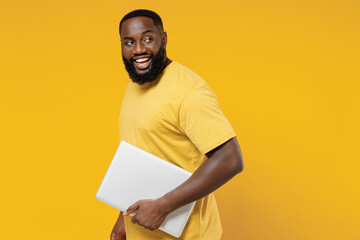 Young smiling copywriter fun happy black man 20s wearing bright casual t-shirt hold use closed...