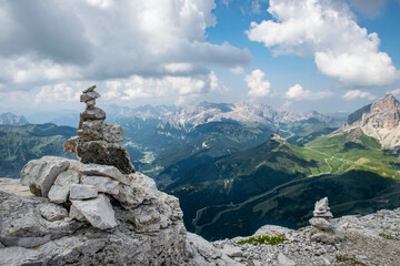 Dolomites, August, 2017, stone pyramids of desires at the top of Passo Fedaia, view of the green valley from above and mountains in the distance