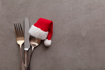 Silver knife fork and spoon with a Santa Claus red festive hat. Christmas meal background