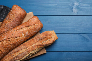 Tasty buckwheat baguettes on blue wooden table, flat lay. Space for text