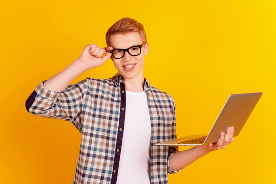 Photo of young cheerful guy eyewear economist banker use laptop isolated over yellow color background