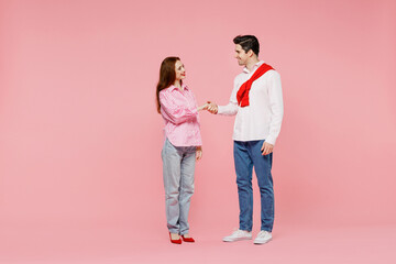 Full body young couple two friends woman man in shirt hold hands folded handshake gesture, isolated on plain pink background. Valentine's Day birthday holiday party friendship business greet concept.