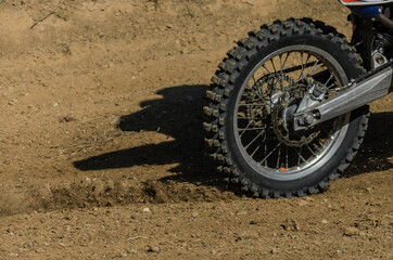 The wheel of a racing motocross motorcycle rides along the race track at high speed, stones and...