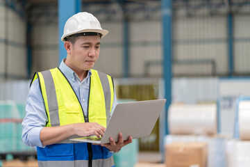 Asian male supervisor engineer hold laptop working at warehouse factory