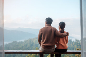 Couple tourist relaxing and looking mountain view at countryside home or homestay in the morning. Vacation, together travel, honeymoon, blogger, journey, trip and relaxing concept