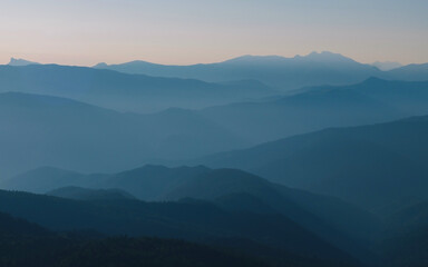 Mountain silhouette layers in the sunset light. Beautiful photography of the nature, blue layered background. Natural gradient.