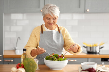 healthy eating, food cooking and culinary concept - happy smiling senior woman making vegetable...