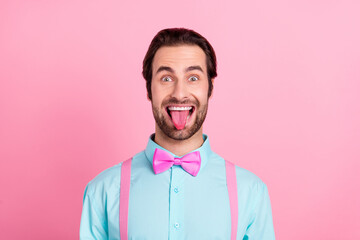 Photo of funny fooling young man wear turquoise outfit smiling showing tongue isolated pink color background