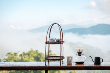 arabica coffee brewing by Vintage coffee drip equipment set on wooden table in the morning with mountain and nature background