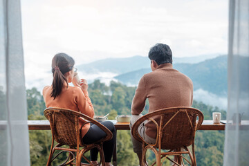 Couple tourist drinking coffee and eating breakfast against mountain view at countryside home or...