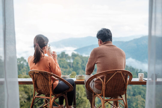 Couple tourist drinking coffee and eating breakfast against mountain view at countryside home or homestay in the morning. Vacation, together travel, honeymoon, blogger, journey and trip concept - Powered by Adobe