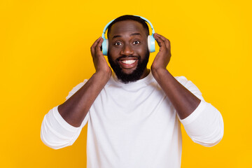 Photo of satisfied candid person hands touch headphones toothy smile isolated on yellow color background