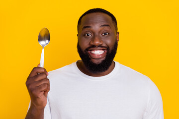 Portrait of funky satisfied person hand hold spoon toothy smile look camera isolated on yellow...