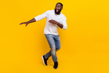 Fototapeta na wymiar Full size photo of cheerful satisfied young man enjoy clubbing look empty space beaming smile isolated on yellow color background