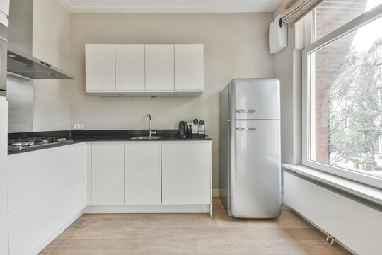 Modern furnished kitchen interior with wide window and fridge