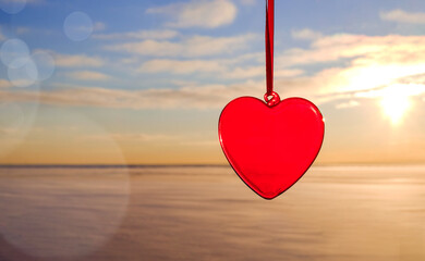 The red heart on string on blue sky and snow background with bokeh