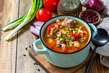 Traditional English thick soup with beef, beans and vegetables on a wooden table. Hot dinner or lunch. Copy space.