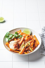 Baked sweet potato wedges with hummus, nuts and seeds in bowl. Healthy vegan food concept.