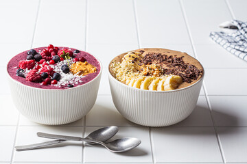 Chocolate and berry smoothie bowls on white background. Raw vegan food concept.