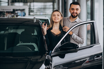 Young couple choosing a car in a car show room