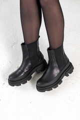 Black elegant shoes on women's legs. Leather winter boots, stylish lady footwear concept photo