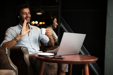 Plakat Handsome businessman working on laptop and sitting in cafe. Young man having video call