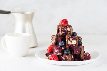Pieces of beet brownie with berries and chocolate without baking. Sugar, gluten and lactose free and vegan.