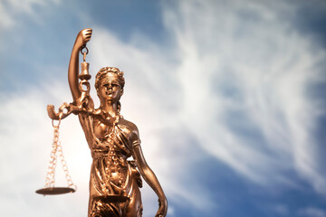 Fototapeta premium statue Themis representing justice and fairness with blue sky with clouds unfocused in background