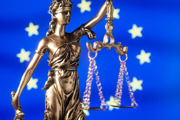 statue Themis representing justice and fairness with European Union  flag  unfocused in background