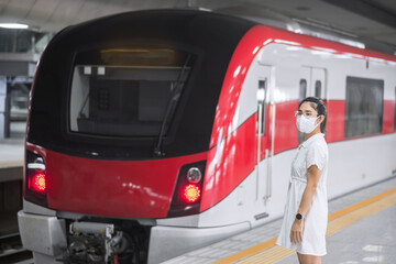 woman wearing Protective face mask prevention coronavirus inflection during waiting train. public...