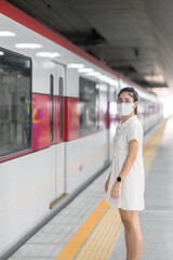 woman wearing Protective face mask prevention coronavirus inflection during waiting train. public...