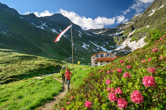 Man and woman hiking in Virgental during spring with Bergerseehutte in background