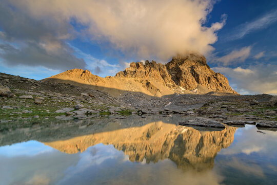 Mountain reflecting on surface of clear lake in Maira Valley